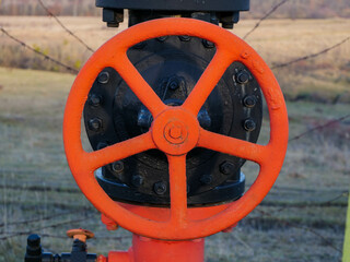 Red painted steel gas pipe valve close up shot for industrial background.