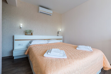 Interior of a bedroom with white walls and a large double bed with a white blanket in the hotel