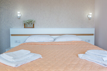 Fototapeta na wymiar Interior of a bedroom with white walls and a large double bed with a white blanket in the hotel