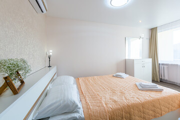 Fototapeta na wymiar Interior of a bedroom with white walls and a large double bed with a white blanket in the hotel