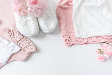 Summer clothes for girls and sneakers decorated with delicate pink flowers on a white background