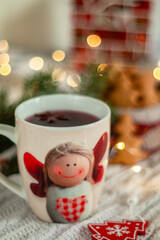 A cup of hot Christmas drink with spices on a blurred background. Cup with angel.