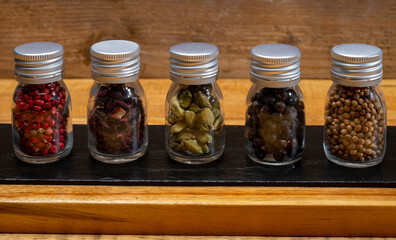 Professional set of gin spices in small bottles, pink pepper, hibiscus flowers, juniper berries, cardamom and coriander seeds