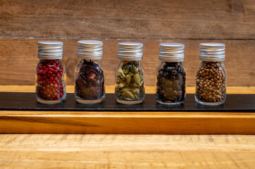 Professional set of gin spices in small bottles, pink pepper, hibiscus flowers, juniper berries, cardamom and coriander seeds