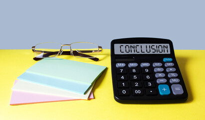 The word conclusion on the display of the calculator on a yellow-blue background with stickers and...