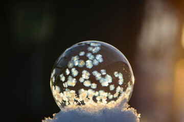 A frozen bubble in the snow with bokeh in the background. Beautiful frosty patterns on a frozen...