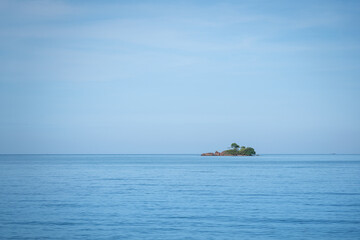 A small island in far distance on the ocean and horizontal line with clearly blue sky. Seascape...