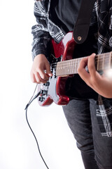 Vertical image of young man dressed in black playing guitar on white background.