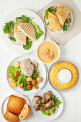 Set lunch - soup, chicken, potatoes, lettuce, cheese, roll, cakes, vegetables and casserole. Top view