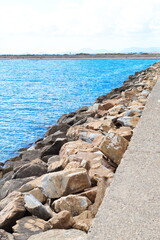 Fototapeta na wymiar Concrete dam with defense rocks from the waves of the sea on a sunny day