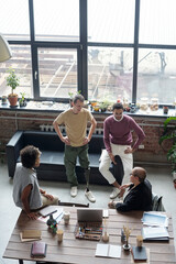 Group of young co-workers in casualwear discussing ideas for new business project at meeting in...