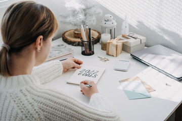 2022 goals, New year resolution. Woman in white sweater writing Text 2022 goals in open notepad on...