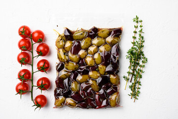 Olives in vacuum packaging for supermarket, on white stone table background, top view flat lay