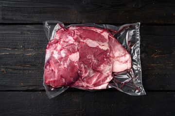 Vacuum packed meat, on black wooden table background, top view flat lay, with copy space for text
