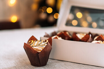 Celebratory cupcake in brown wrapper in front of white cardboard box