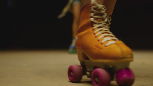 Female legs in roller blades, skating fast at the roller park on floor . Close-up legs of young women is professionally skating . Different kind of and colorful vintage roller blades . Slow Motion
