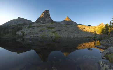 Russia. Krasnoyarsk Territory. Reflections of harsh rocks in the lakes of the Ergaki Natural Mountain Park.