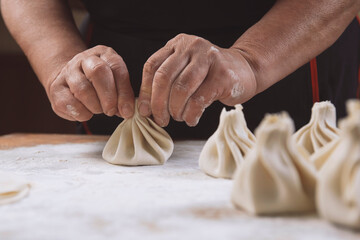 Chef cook making khinkali  on wooden table. Process preparation georgian meal. food concept.