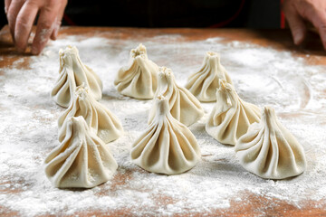 Chef cook making khinkali  on wooden table. Process preparation georgian meal. food concept.