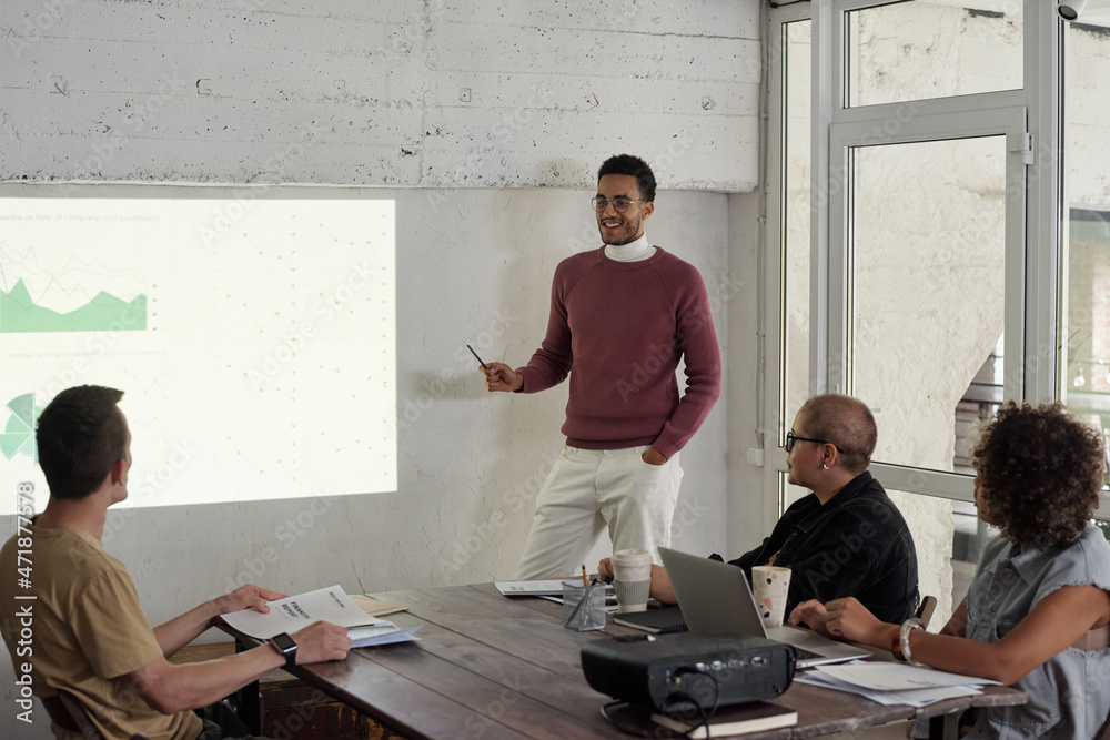 Poster young successful business coach standing by interactive whiteboard while explaining financial data t