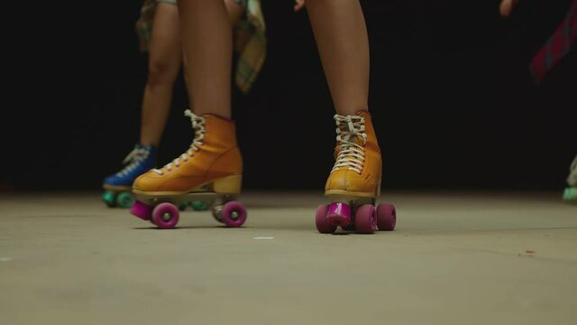 Female legs in roller blades, skating fast at the roller park on floor . Close-up legs of young women is professionally skating . Different kind of and colorful vintage roller blades . Slow Motion