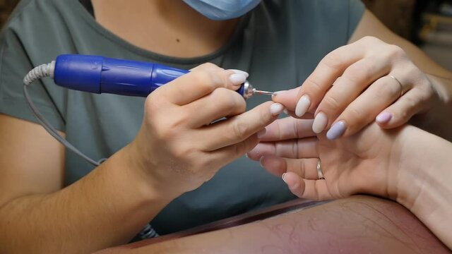hardware manicure. The master grinds the skin on the border with the nail with a round working attachment with a manicure machine. Slow motion