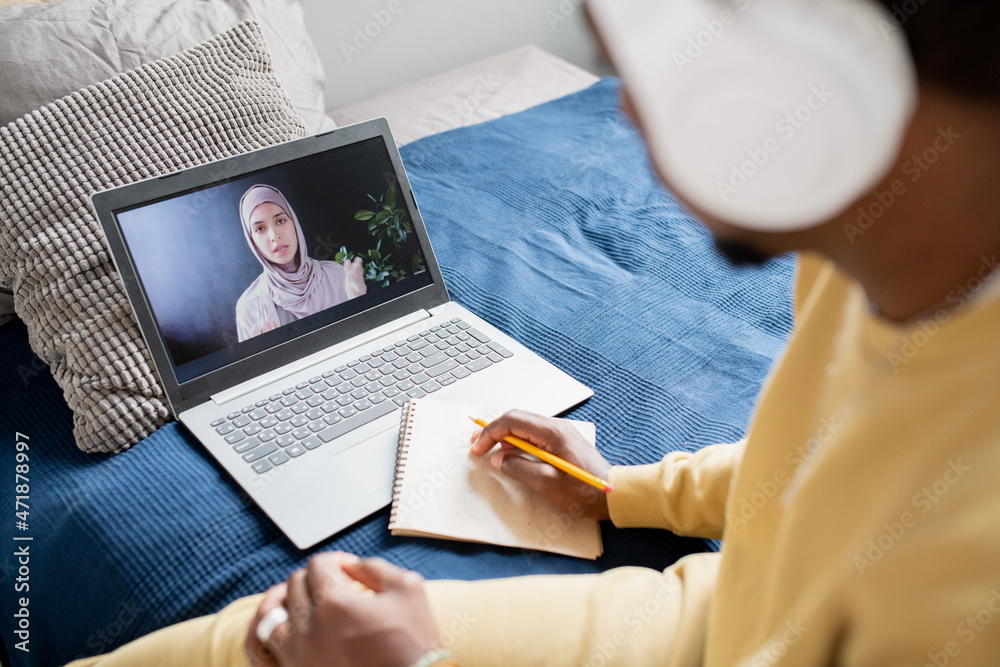 Poster young confident teacher in hijab explaining point of lesson to student with pencil and notepad durin