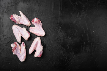 Raw turkey wings, on black dark stone table background, top view flat lay, with copy space for text