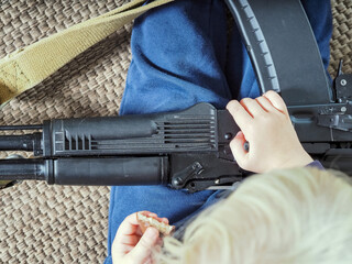the child is playing with a weapon. a machine gun in the hands of a little boy