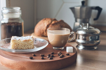Morning still-life in the kitchen with the jar of coffee, beans, coffee pot, sugar bowl, sugar cube, fresh homemade cakes, bread and cup of latte. healthy home cooking. Tasty Breakfast concept