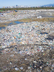 Drone view of a large landfill, a pile of garbage. Household waste in a landfill, waste disposal in a landfill. Concept of ecology, consumerism. Vertical photo