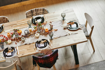 Part of long wooden dining-table served with kitchenware and decorations symbolizing autumn festivity