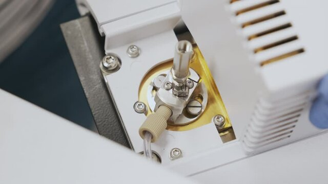 Close up scientist insert a nebulizer needle into into source of mass spectrometer. Liquid chromatography with mass detection for pharmaceutical analysis. Maintenance of LC MS qTOF