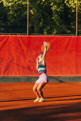 Pretty sportswoman with racquet playing tennis on a sunny day