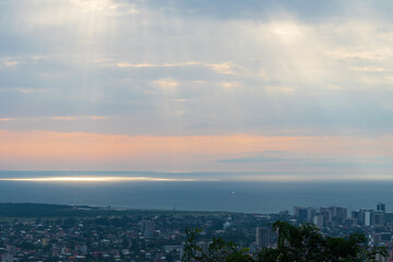 View from the mountains to Batumi, the rays of the sun shining into the sea, a plane flying away. Beautiful, fascinating view of the city of Batumi