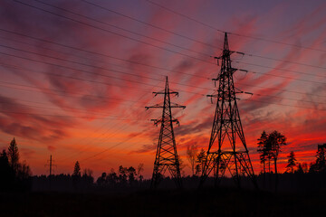 Electric pylons in the Estonian countryside in autumn during sunset. Dramatic sky in the background.