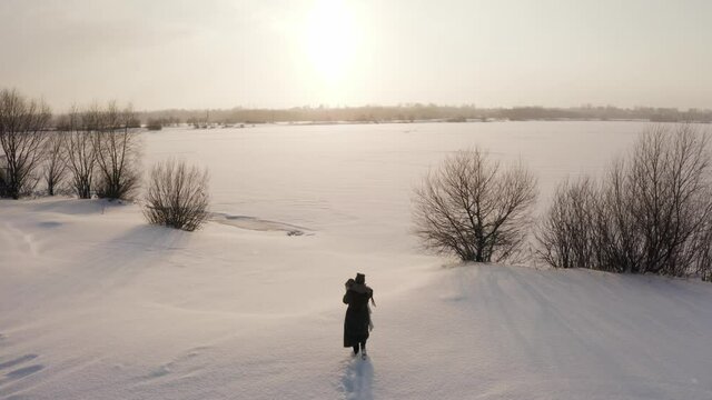 Top view of a girl walking in a snowy field with a dog in her arms