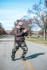 Handsome happy man standing in an empty street wearing a cool brown jacket and camo pants.