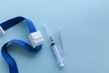Taking blood for analysis. syringe and venous harness on a blue background, flat lay with space for text. Vaccination and immunization
