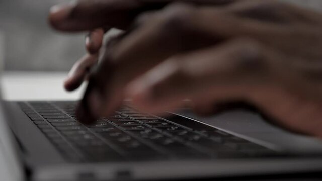 Close up hands African American man doctor typing text on keyboard laptop in clinic office. Medical worker working and uses computer enters patient documents into electronic database at hospital