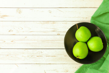 Golden green apples in a dark plate on a table of tables accompanied by green cloth