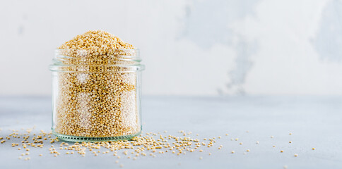Raw quinoa grains in jar. Healthy vegetarian food on gray kitchen table. Selective focus