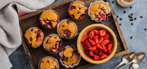 Strawberry chocolate cupcakes muffins on old wooden stand on concrete gray background. Top view