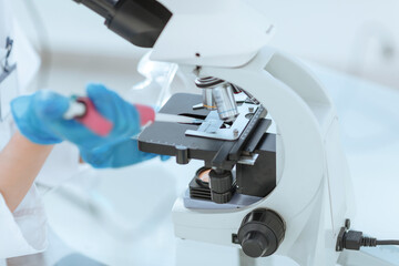 close up. Scientist analyzing microscope slide at laboratory.
