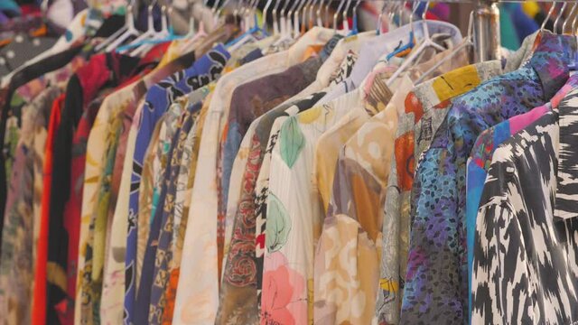 BARCELONA SPAIN - JANUARY 5 2020: Vintage second hand hat and clothes rail showing colourful vintage clothes on coat hangers.