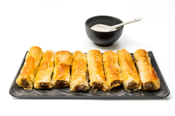 
Meat rolls pastry - fried minced pork meat in spring rolls in an oval plate with a bowl of tartar 

sauce and stack og rolls in the background, selective focus, isolated on white background