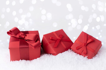 Red gifts in the snow with bokeh lights.