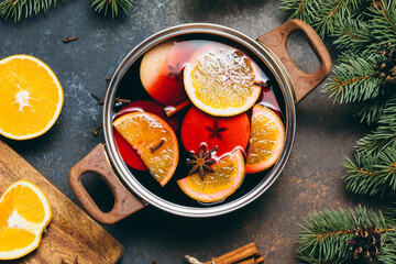Hot Mulled wine cooking at home for happy christmas time. Red wine, orange, apple and spices -...