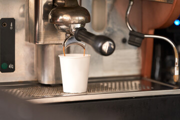 Street coffee shop. Coffee pours from the holder of the coffee machine into a paper cup. Selective focus.