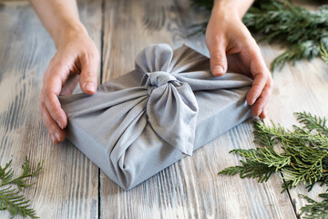 Female hands holding a christmas gift wrapped in cloth.